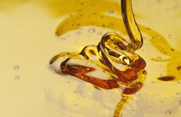 Pure golden manuka honey pouring into a glass jar